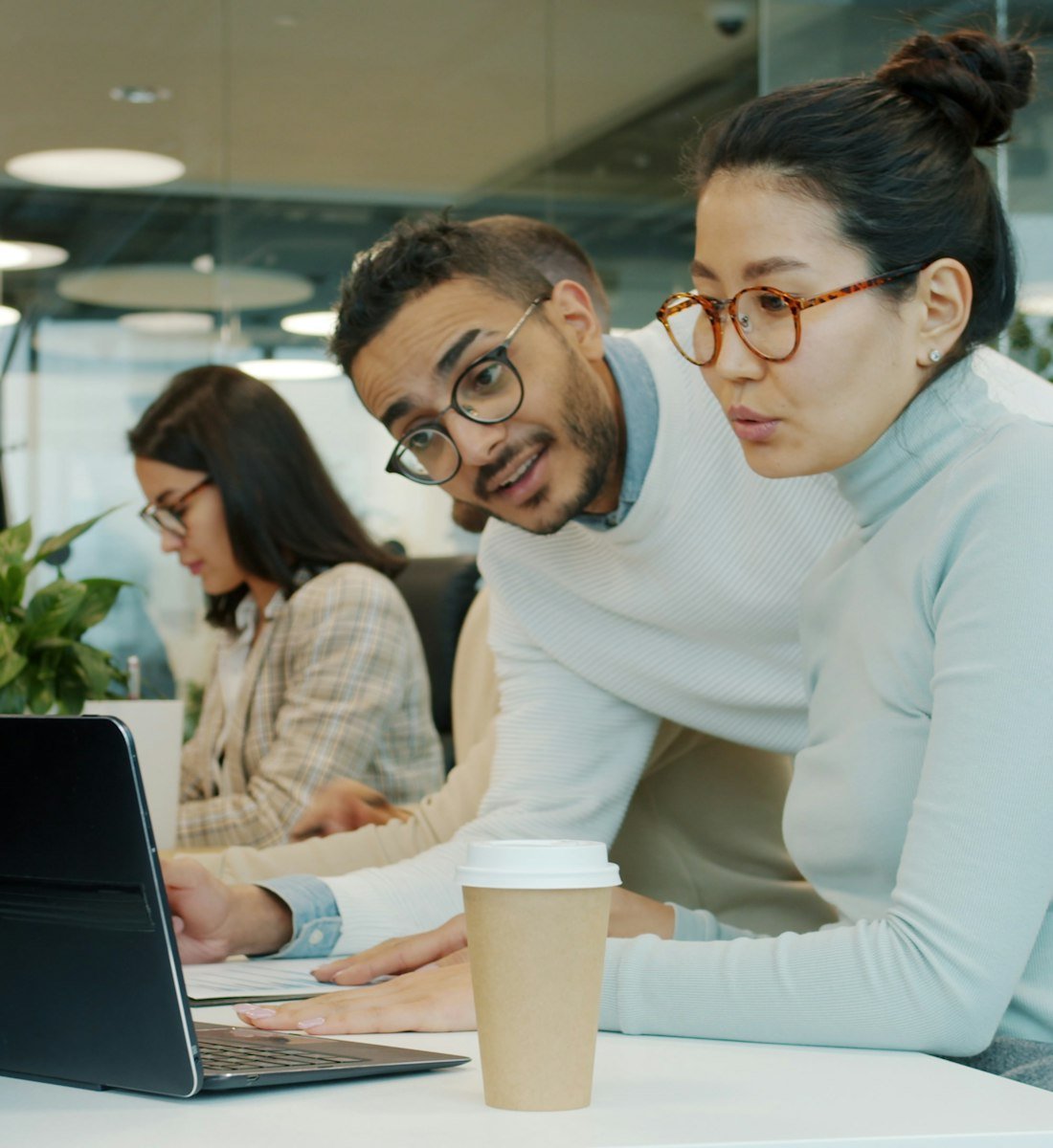 Two colleagues reviewing work together on a laptop in a bright office